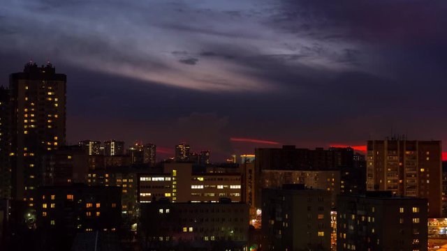 Time lapes cities. Evening shooting of houses, the sun sets, hides behind the clouds. On the street, night falls.