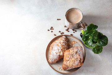 Cup of black coffee with foam and croissants on a light concrete background. Breakfast concept.