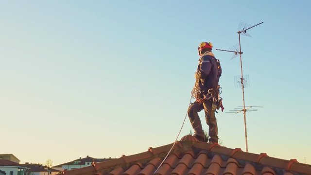 Industrial rope access man wearing safety harness on top of a roof