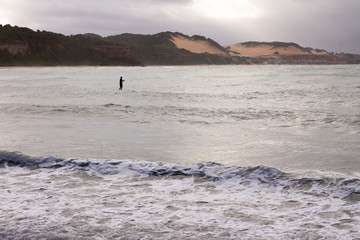 Silhouette of a man practicing Stand up Paddle on a stormy day.