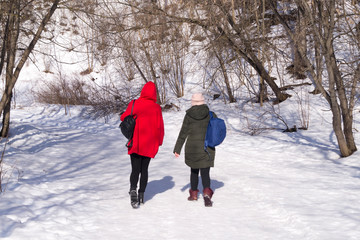 girls are walking on a winter road in a park