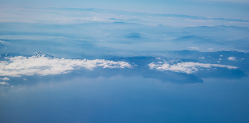 Fototapeta premium View from airplane over the land with mountains and clouds