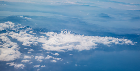View from airplane over the land with mountains and clouds