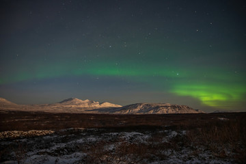 Northern lights above snow-covered mountains in Iceland