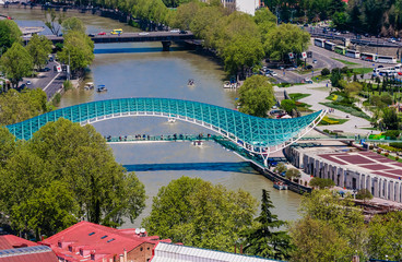 Fototapeta premium View Of Kura Mtkvari River Under Bridge Of Peace And Baratashvili Bridge, Embankment And City Neighborhood, Tbilisi, Georgia