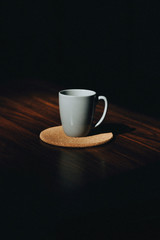 A fresh cup of coffee placed on a table with a cork saucer.