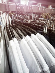 White T-shirts hang on hangers in a row at a clothing store. The concept of buying, discounts, sales, business.