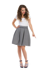 Young Woman In Striped Skirt Is Pointing Down And Looking