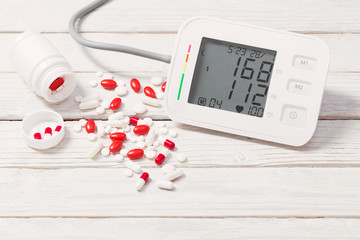 modern tonometer with pills on wooden background