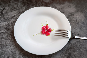 Ripe raspberries on a white plate. Near a metal plug.