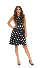 Beautiful Young Woman In Black Cocktail Dress In Polka Dots And High Heels. Front View.