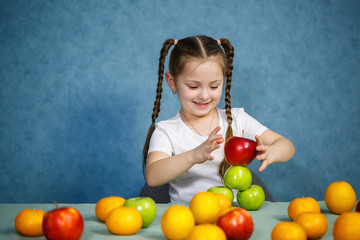 Little girl in white T-shirt plays and poses with fruit