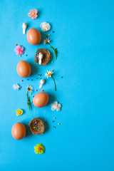 Easter pattern of Eggs with flowers, nests and candies on the blue background. Easter concept. Healthy feeding concept. 