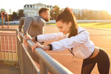Girl and man in sportswear doing warm-up at the stadium