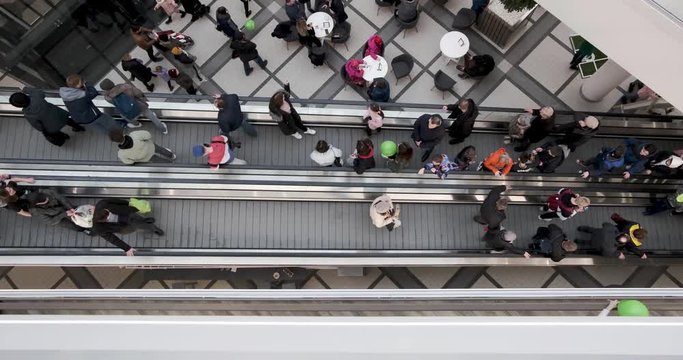 Crowd Of People On An Escalator In A Large Multi-storey Layered Shopping Center. View From Above