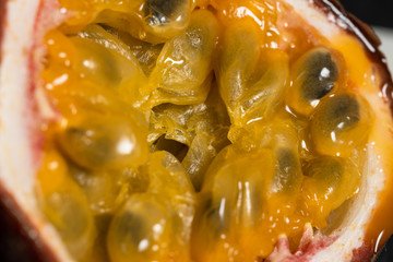 cut in half fruit passion fruit on a black campa lies next to a ceramic knife