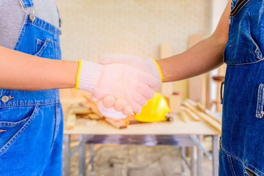Two handyman standing with shaking hand after successful about to partnership.