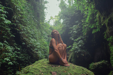 Fototapeta na wymiar Sexy young girl in a green swimsuit in a tropical jungle. Bali.