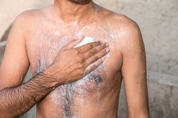 a young man is washing his body by a soap
