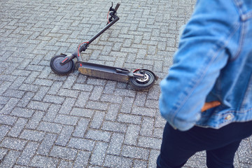A broken electric scooter lies on the pavement on a city street © Studio Romantic
