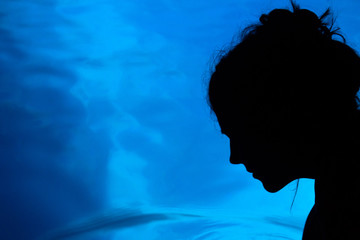 Silhouette shadow of woman head on beautiful blue glowing sea surface