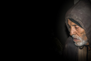 sad expression of an elderly sick man in a dark room 
