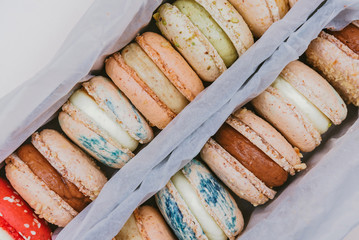 Assorted macaroons in box on pastel beige background. Top view.