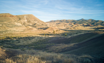 Incredible gold and red hills of clay fossil beds in a semi desert mountain valley on a sunny day of the painted cove trail at the john day fossil beds in Oregon