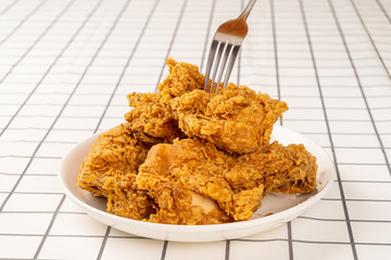 Close Up Hand and Fork on Fried Chickens on white Plate Isolated on table. Look Yummy and Yellow Gold Color.