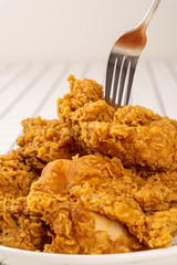 Close Up Hand and Fork on Fried Chickens on white Plate Isolated on table. Look Yummy and Yellow Gold Color.
