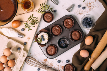 cupcakes with cream and blueberries on kitchen table