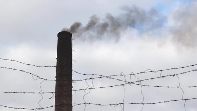 Black smoke burning from a factory chimney, released in the air polluting atmosphere and environment.