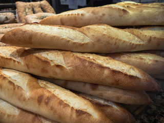 A stack of freshly-baked French bread baguettes on sale at an traditional artisan bakery in a public market in Vancouver, Canada.