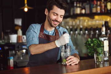 Drink Preparation. Bartender standing at counter squeezing out lime juice smiling concentrated - obrazy, fototapety, plakaty