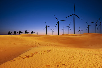 Renewable energy in desert sand dunes at sunset concept with solar panels and wind turbines