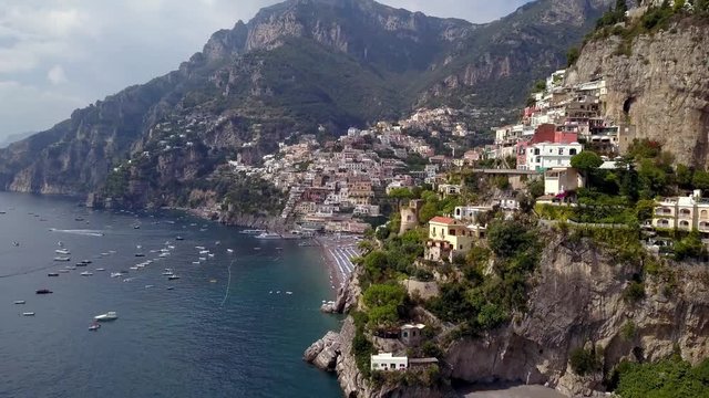 Positano in the Italian Amalfi coast seen from the side showing colorful hillside mansions, Aerial left pan reveal shot
