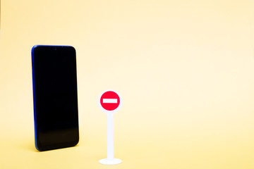 toy stop sign and smartphone on a yellow background, digital detox concept, copy space