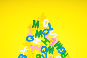 ABC wooden letters alphabet scattered on a yellow background. Education and copy space