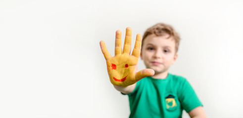 Close up little boy with hands painted with yellow paint