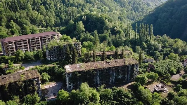 Ruined lost overgrown mining ghost town Akarmara, consequences of war in Abkhazia, aerial view from drone.