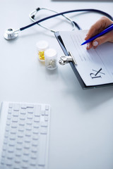 Woman's hands writing on sheet of paper in a clipboard with pen isolated on desk