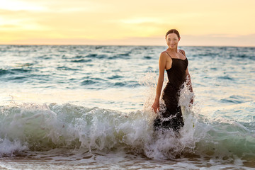 Beautiful woman by the ocean at sunset