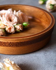 Roses in a wooden decorative bowl on a gray background. Copy space. Happy mother's day. Vertical orientation