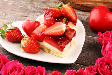strawberry cake and many fresh strawberries on rustic table with hearts and roses for valentines day.