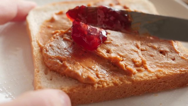 spreading marmalade, jam on a peanut butter sandwich