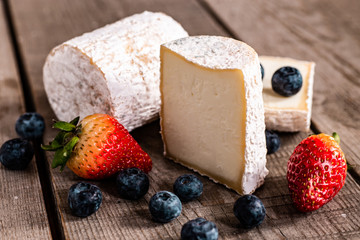 Goat cheese and berries on a wooden background