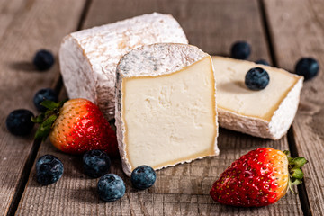Goat cheese and berries on a wooden background