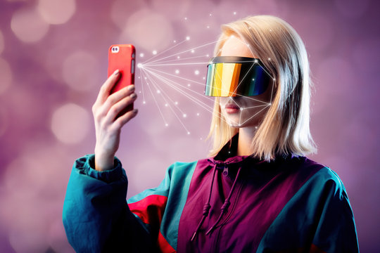 Blonde in VR glasses hold mobile phone with face scanning algorithm