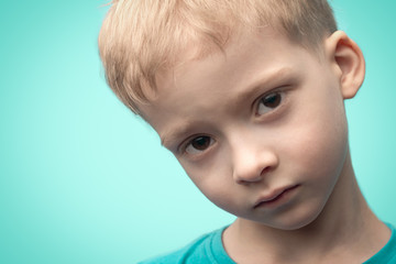 portrait of a child on a blue background close-up. the boy's face close-up