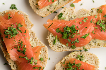 Trout sandwiches with herb butter and parsley lying on a white plate shot from above